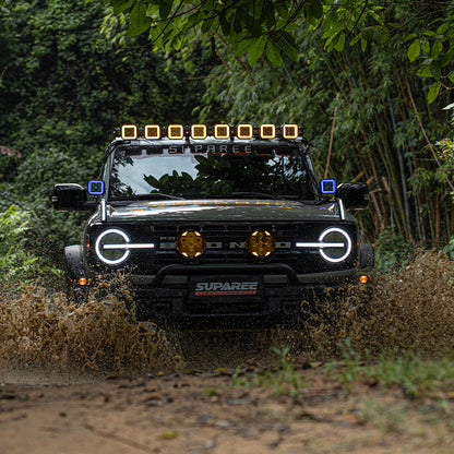 Off-road vehicle crossing water with SUPAREE HYPER 5 pod lights on the roof and beside the windshield.