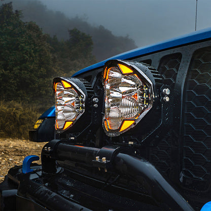 Close-up of two SUPAREE HELM 7-inch LED driving lights with clear lenses and amber DRLs on a Jeep bumper.