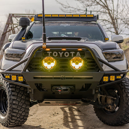 SUPAREE HELM 7 LED driving lights shining through amber covers on the front bumper of a Toyota truck.