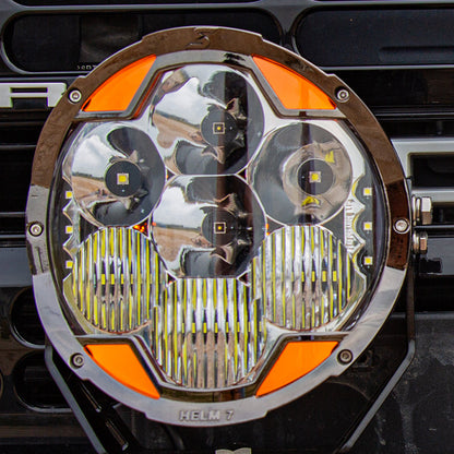 Front view of a SUPAREE HELM 7 round LED driving light showing its clear lens, reflectors and amber DRL sections.