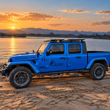 Blue Jeep Gladiator with side steps parked beside the water at sunset.