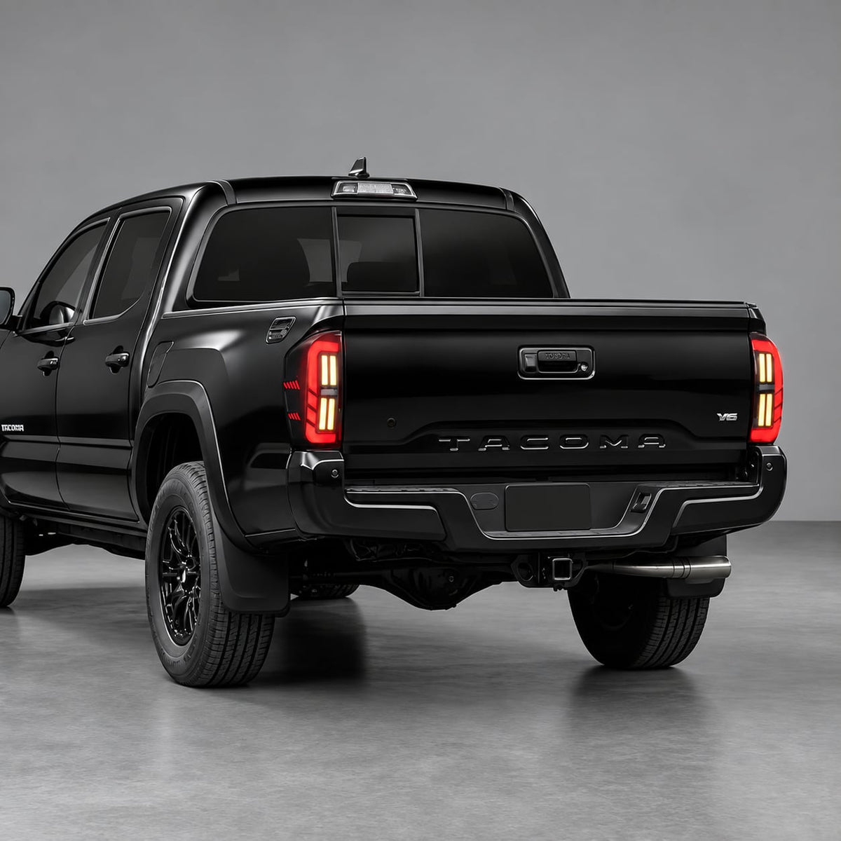Rear three-quarter view of a black Toyota Tacoma fitted with smoked LED tail lights for 2016-2023 models.