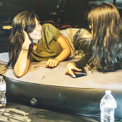 Durable inflatable truck bed air mattress for 2000-2025 Toyota Tundra 5.5FT, shown in use by two women lounging comfortably. Ideal for camping setups.