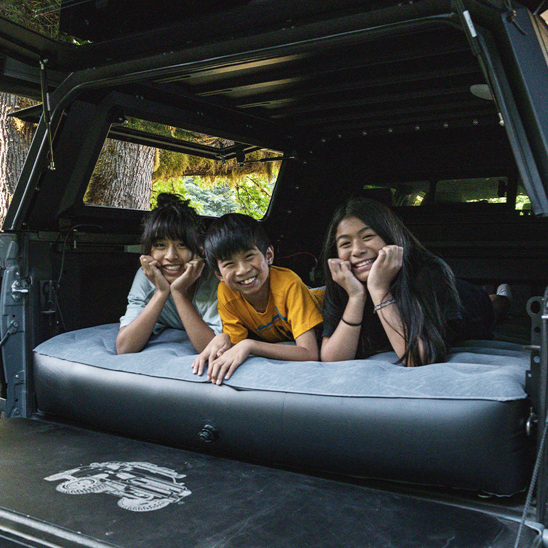 Truck Bed Air Mattress - Tundra Fit shown in use with three kids lying comfortably in the back of a Toyota Tundra 5.5FT bed, ideal for camping.