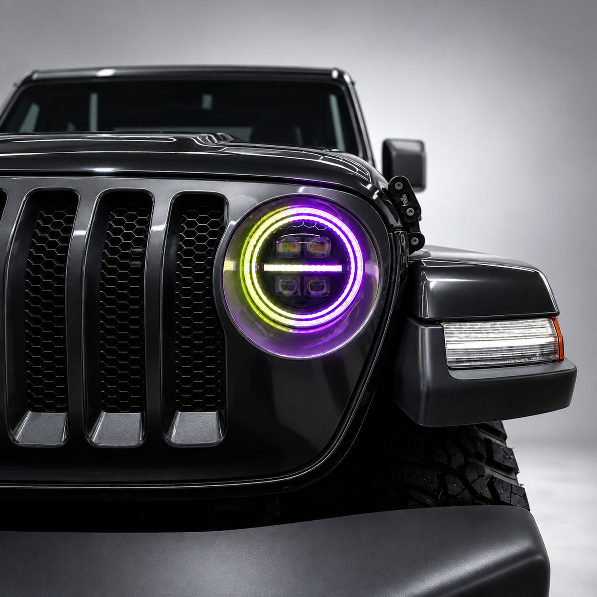 Close-up of a 9-inch Jeep RGB LED headlight with purple and yellow-green dual halo lighting