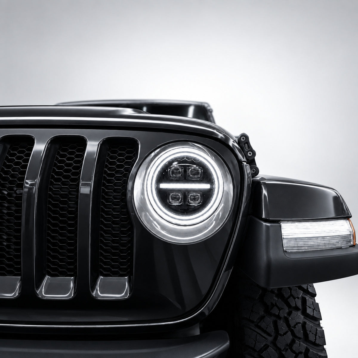 Close-up of a 9-inch Jeep RGB LED headlight with white dual halos, center DRL bar and four projector lenses