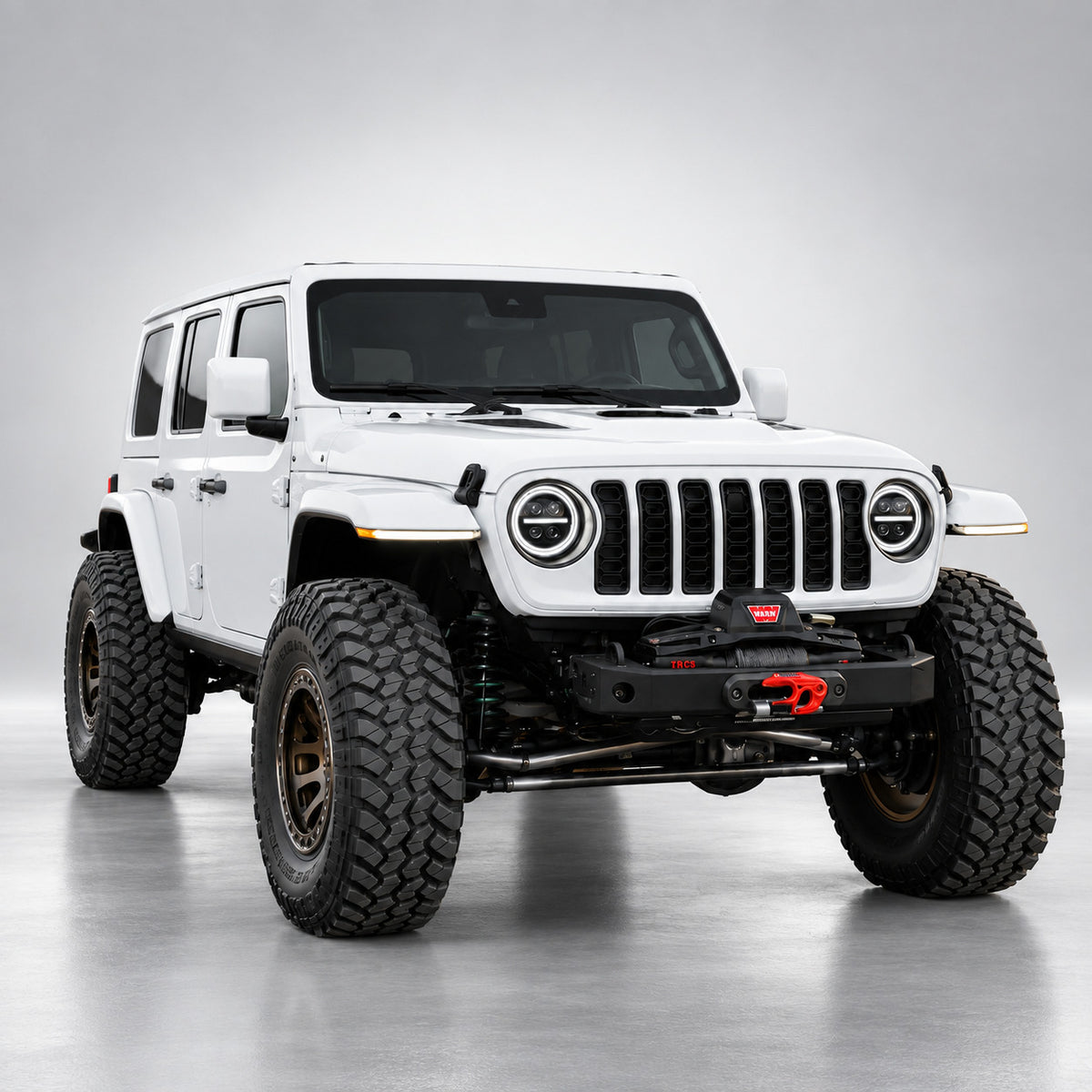 White four-door Jeep Wrangler JLU with 9-inch LED headlights and white DRL rings, front three-quarter view
