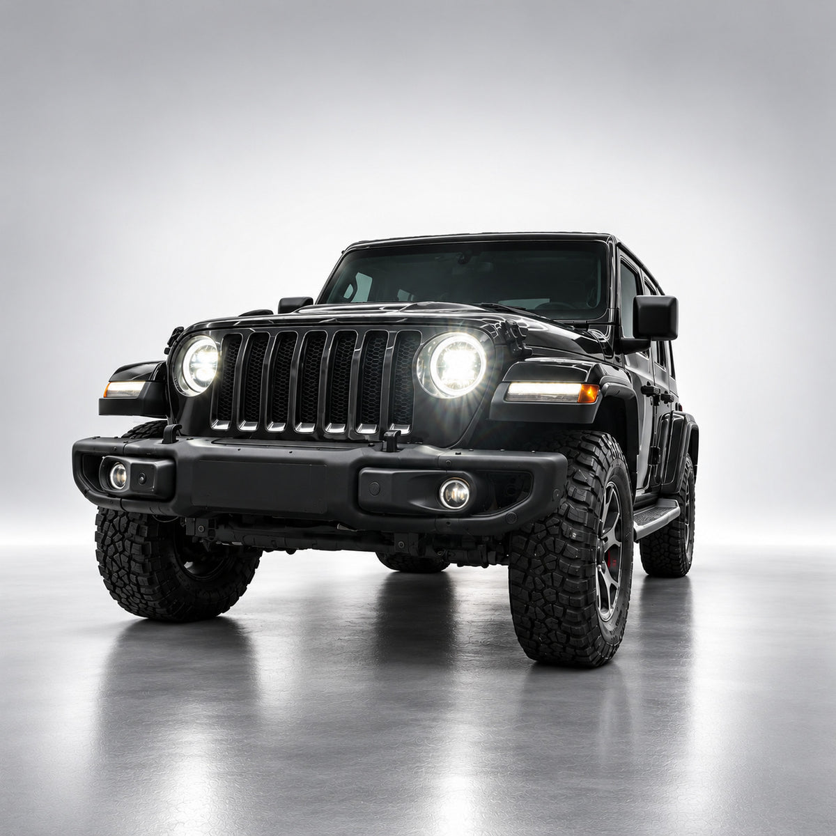 Black Jeep Wrangler JL with white LED headlights illuminated, front three-quarter view